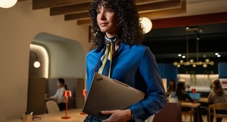 Une femme porte un portable Lenovo ThinkPad X9 dans un café.
