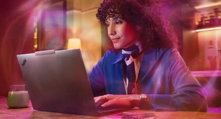 Une femme assise à une table tape sur un portable Lenovo ThinkPad X9