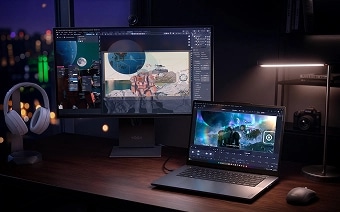 A Lenovo Yoga laptop, monitor, headphones, and mouse atop a wooden desk, representing the Yoga ecosystem.
