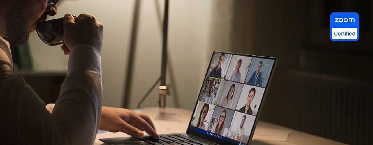 Eine Person sitzt an einem Tisch mit dem Lenovo ThinkPad X1 Carbon Gen 11 Notebook und nimmt an einer Zoom-Konferenz teil.