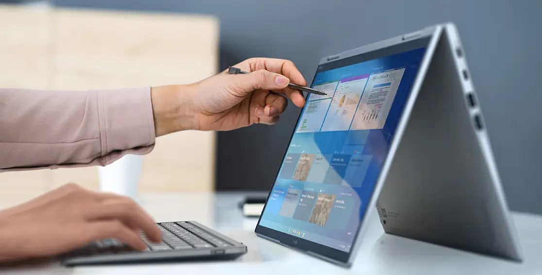 Lenovo ThinkPad X1 Yoga Gen 8 2-in-1 laptop in tent mode next to a wireless keyboard, being used with the integrated pen. 