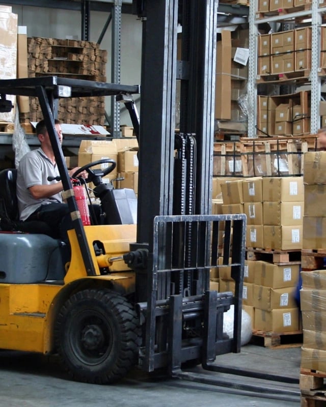 man driving a lift truck in a warehouse