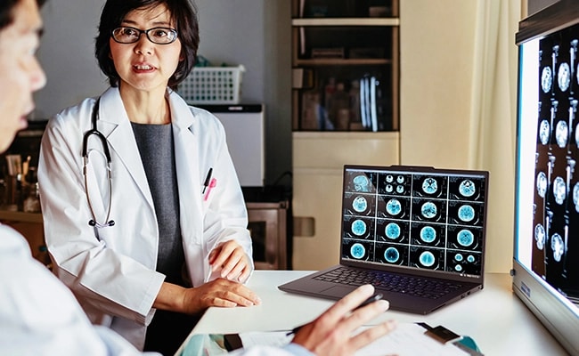 Two medical professionals discussing a report opened on the Lenovo ThinkPad P14s Gen 5 (14 inch Intel) black laptop & on another big screen, highlighting its high-end processing power & performance with data.