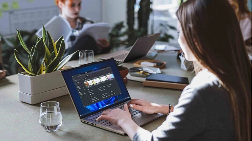 Multiple people gathered around a table and working on their laptops