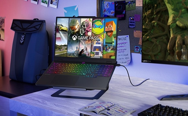 Laptop Lenovo Legion 5i 10ma Gen (15" Intel) para videojuegos montada en un soporte sobre un escritorio: vista delantera derecha, tapa abierta, con el PC Game Pass en la pantalla