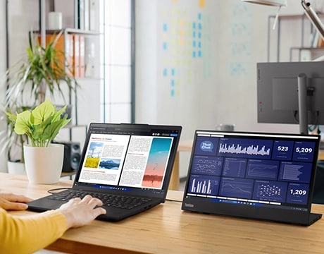 Lenovo ThinkPad L14 Gen 6 (14" AMD) laptop on a desk with a pair of hands on the keyboard and connected to a ThinkVision monitor – right-front view, lid open