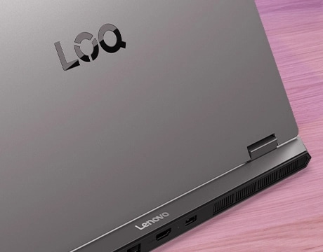 Lenovo LOQ Essential 15IRX11 gaming laptop on a desk – rear view, lid partially open, cropped in close to focus on left hinge.