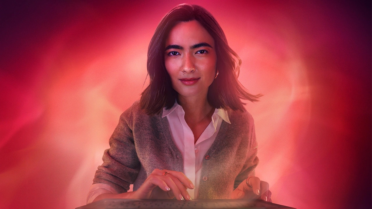 A woman stares into the camera as she presses her fingers to a touchscreen device. 