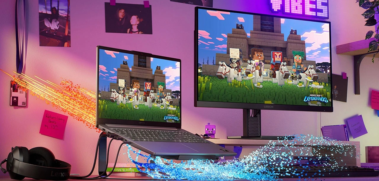 The Lenovo LOQ Essential 15ARP10 gaming laptop on a stand on a desk next to a headset, keyboard, and monitor with Minecraft Legends on both displays and blue and orange lines emerging from the laptop representing thermals. מחשב נייד LOQ&nbsp;15ARP10E 83S0005HIV&nbsp;מבית&nbsp;Lenovo