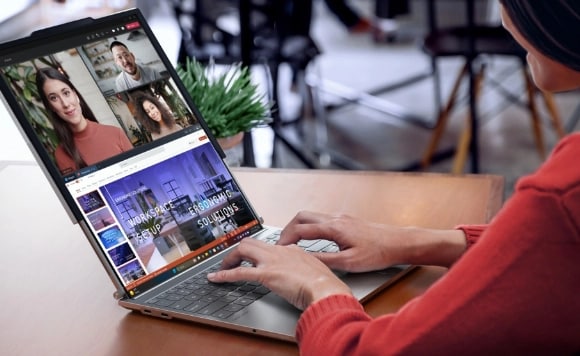 A woman types as she engages in a videocall on a Lenovo ThinkBook laptop.