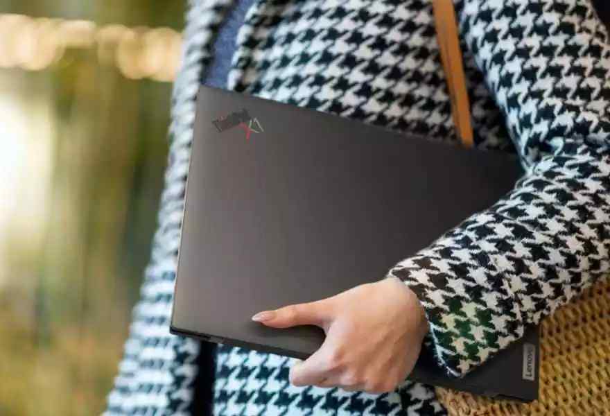 Person carrying ultraportable Lenovo ThinkPad X1 Carbon Gen 10 laptop under their arm