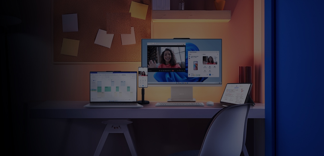 Um tablet visto de lado, um monitor visto de frente, um notebook visto de frente e um celular visto de frente, todos sobre um suporte, em uma mesa de trabalho com um quadro de cortiça na parede.