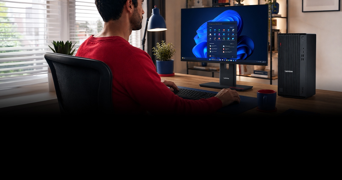 Una PC de escritorio, Lenovo AIO 2 en 1, apoyada en un escritorio y una persona trabajando en ella.