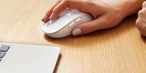 Person using a mouse next to a laptop