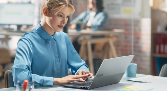 Femmes dans une chemise bleue travaillant dans un étui ouvert ThinkBook 14 Gen 6 Intel (14 »).