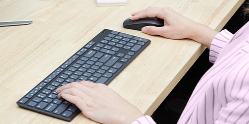 Keyboard on desktop. Person using mouse.