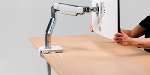 A Humanscale arm is featured on a desk.