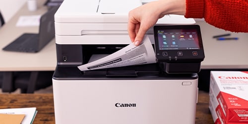 A Canon Megatank and color laser printers is featured on a workplace.