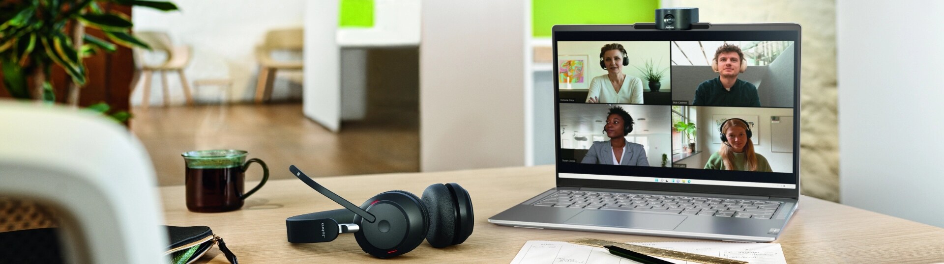 A Lenovo laptop with a screen of a videoconference with 4 people, and the Jabra PanaCast 20 attached to the top of the screen.