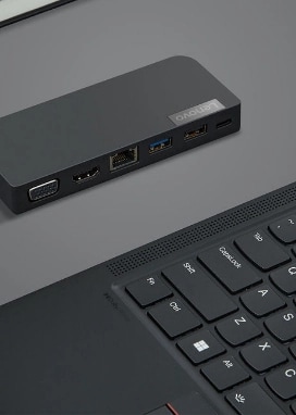 Un portable Lenovo ThinkPad X1 Carbon à côté d’un ThinkPhone sur un bureau gris.