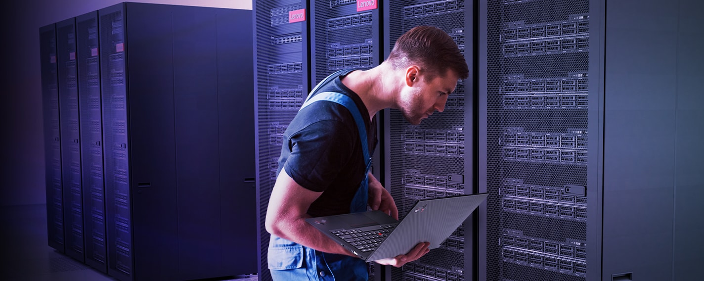 Person using a laptop while inspecting server racks inside a data center. 