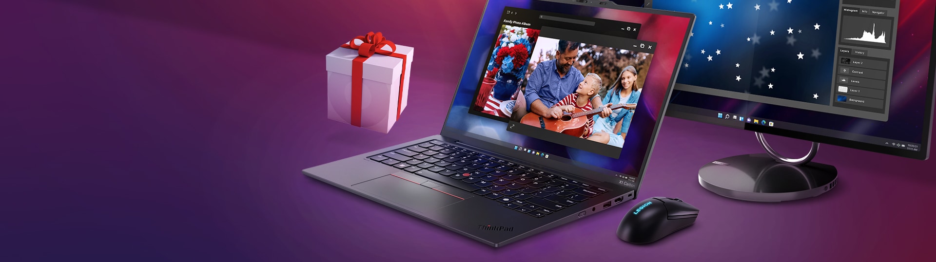 A ThinkPad laptop displaying a family photo, a Lenovo monitor, a lenovo mouse, and a gift box on a purple surface.