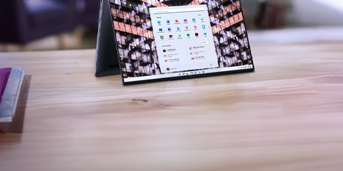 Portable pliable sur une surface en bois affichant une grille d’icônes d’applications et un écran de notification ou de menu.