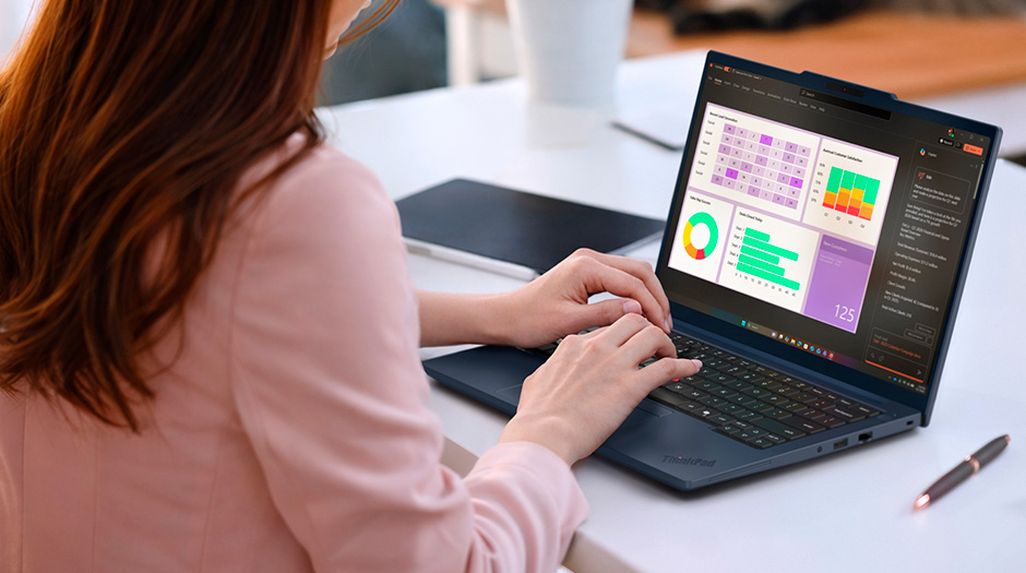 A woman at a desk types on a Lenovo ThinkPad T14 Gen 7 (14” AMD) laptop.