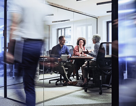 Business team discusses around a conference table in a modern office setting.