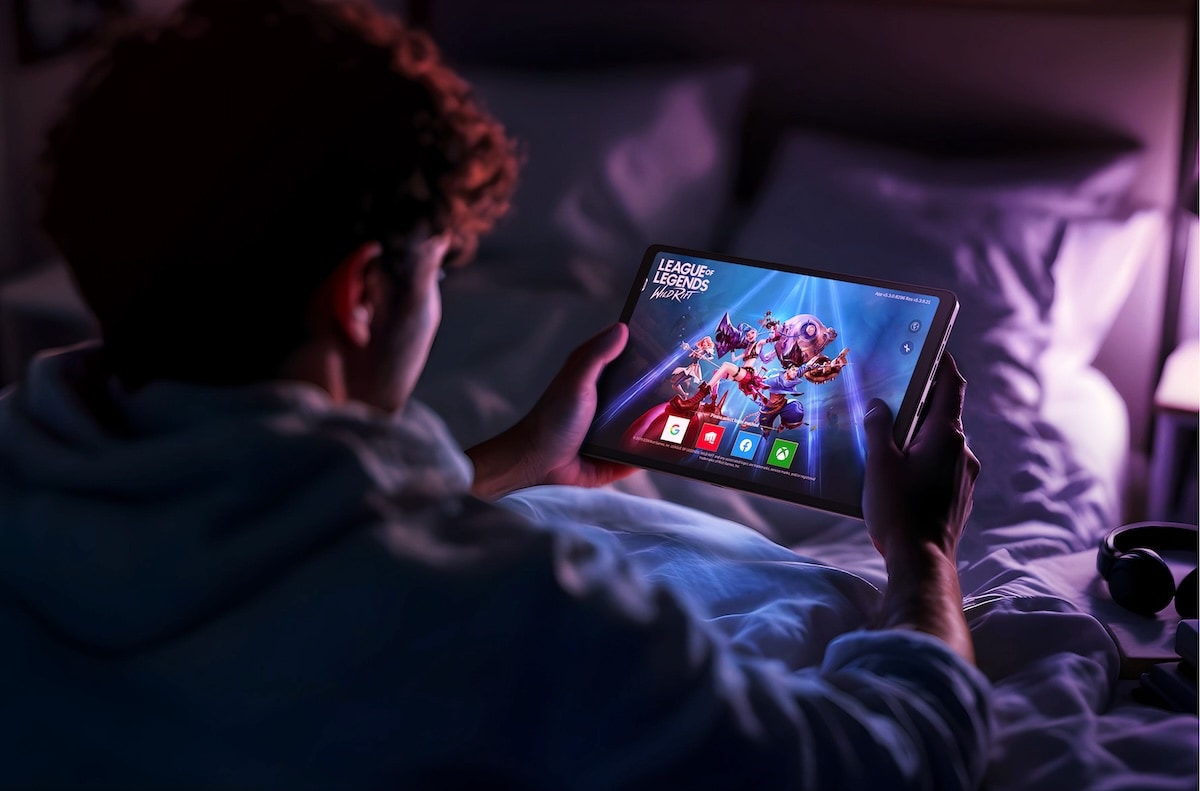 Un adolescent qui joue sur la tablette Lenovo Legion Tab dans une chambre sombre, aux couleurs vives et à l’action rapide à l’écran.