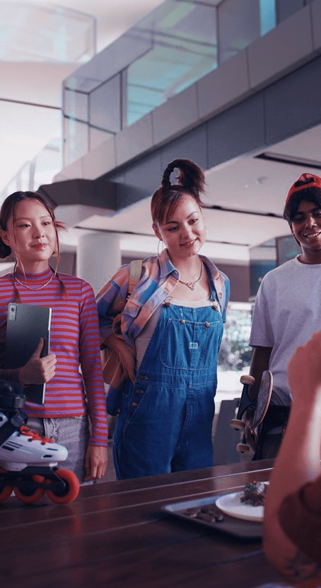A group of young students wealk through a campus hallway, with one woman holding her tablet.