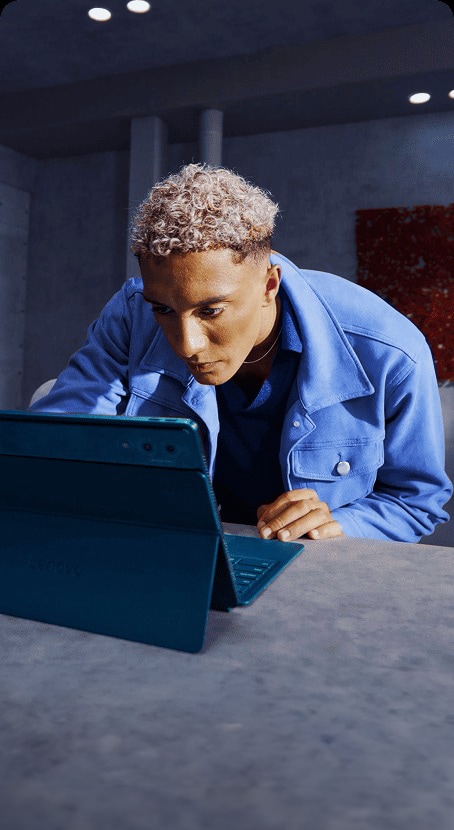 A man focuses intently while working on a Lenovo Yoga tablet at a desk in a modern interior.