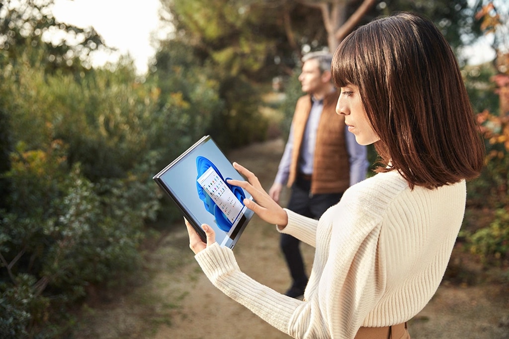 Dışarıda bir bahçede tablet modunda dünyanın ilk 5G dizüstü bilgisayarı olan Lenovo Yoga 5G kullanan biri