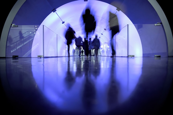 The image shows a crowd of people busily walking through a purple-colored corridor.