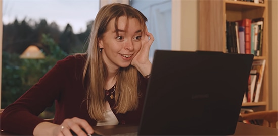 A smiling Maria Kallevik looks at the display of a Yoga laptop.  