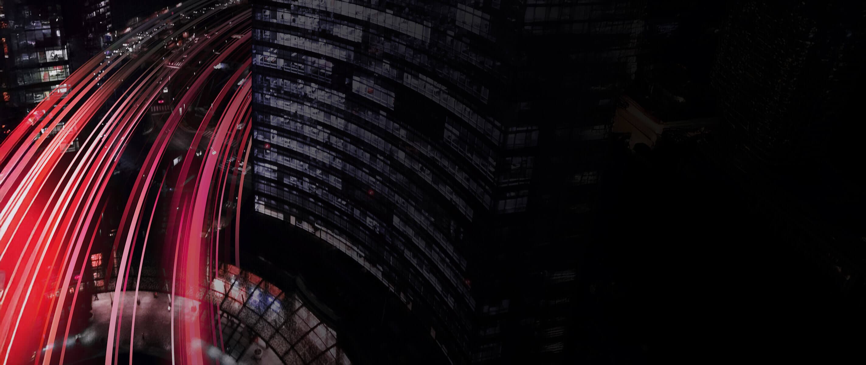 A time lapse of a highway curving around city buildings at night.