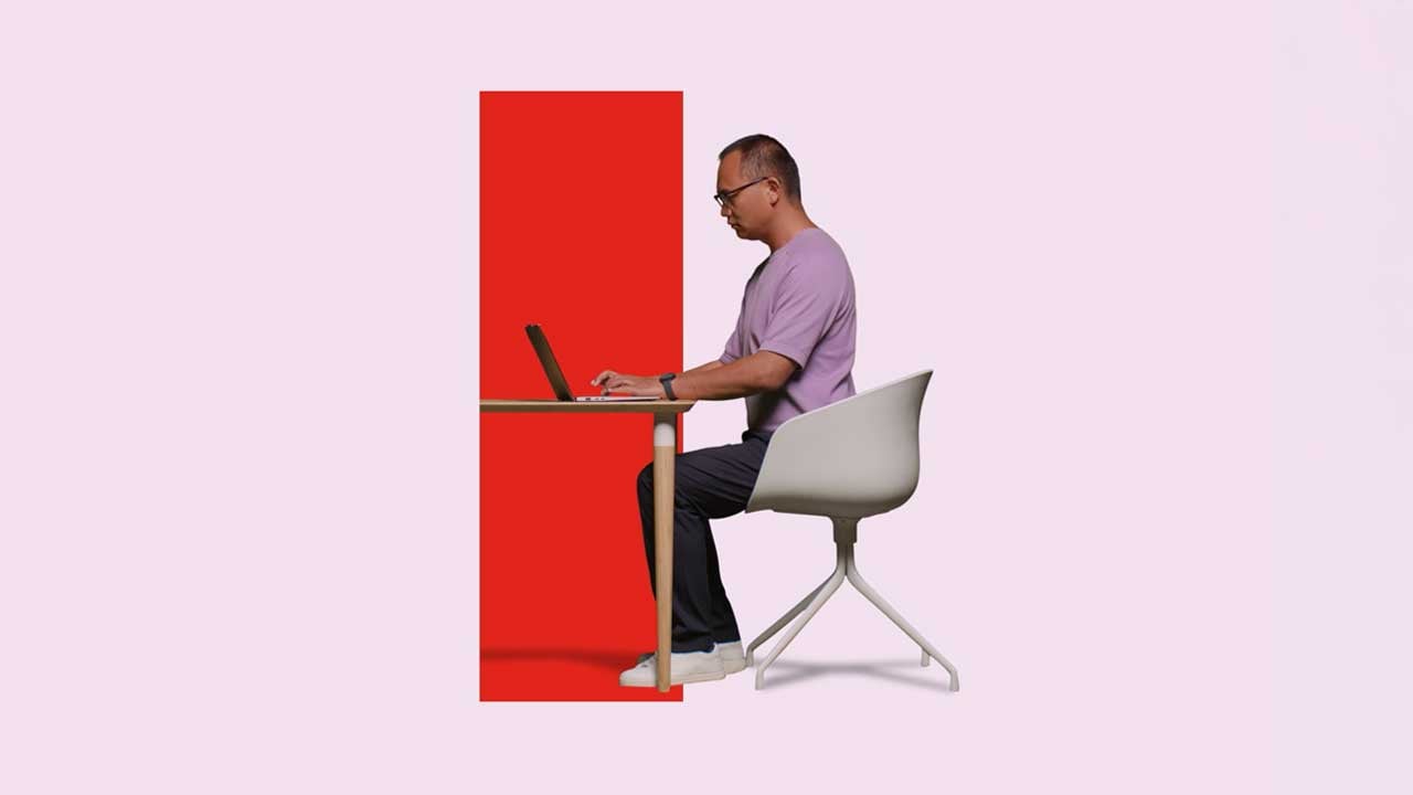 A man working on his laptop at a desk that’s set within a red rectangular portal