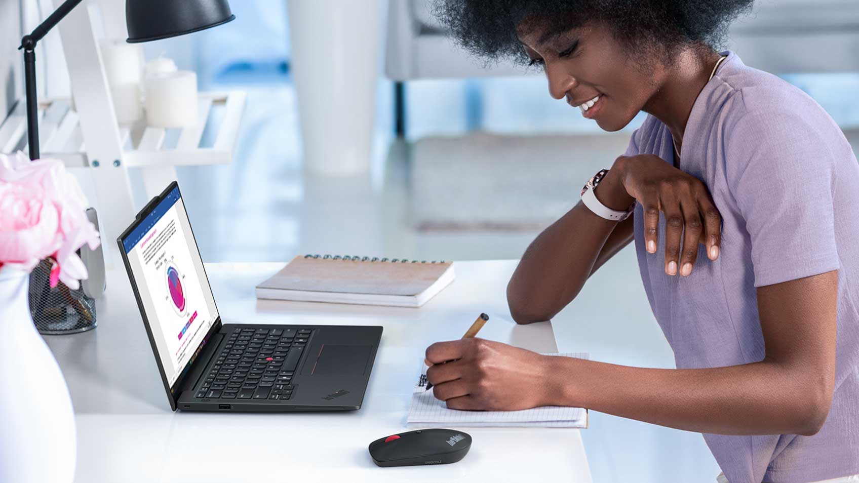 A woman using a laptop and taking notes.