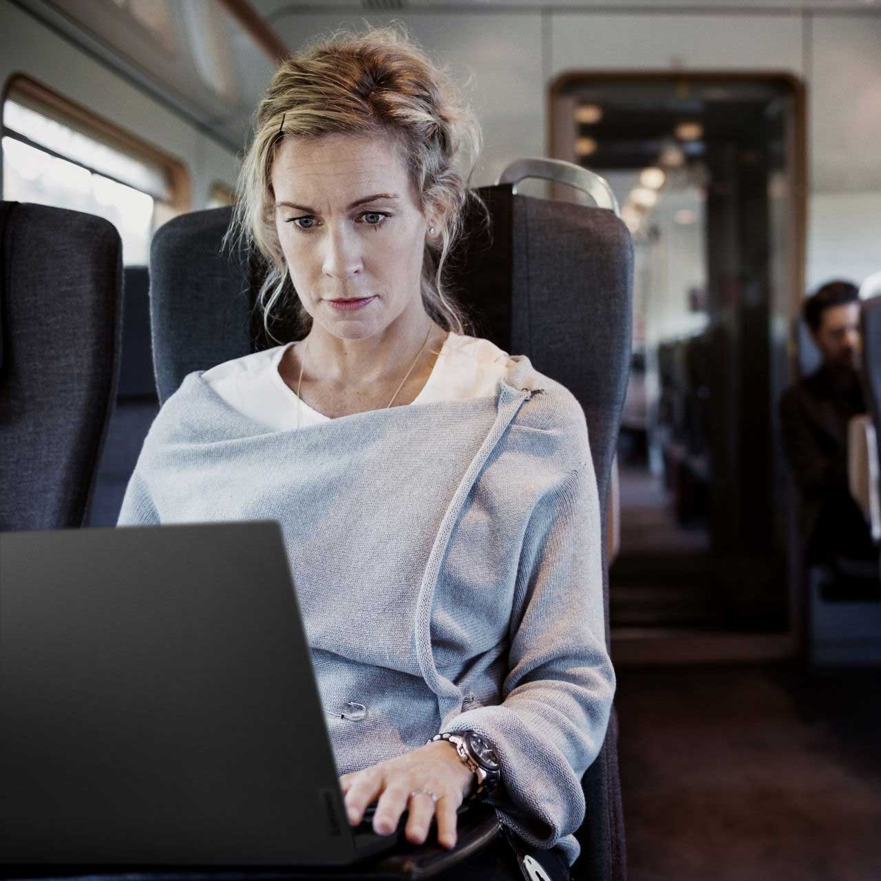 Une femme travaillant sur son portable dans un train.