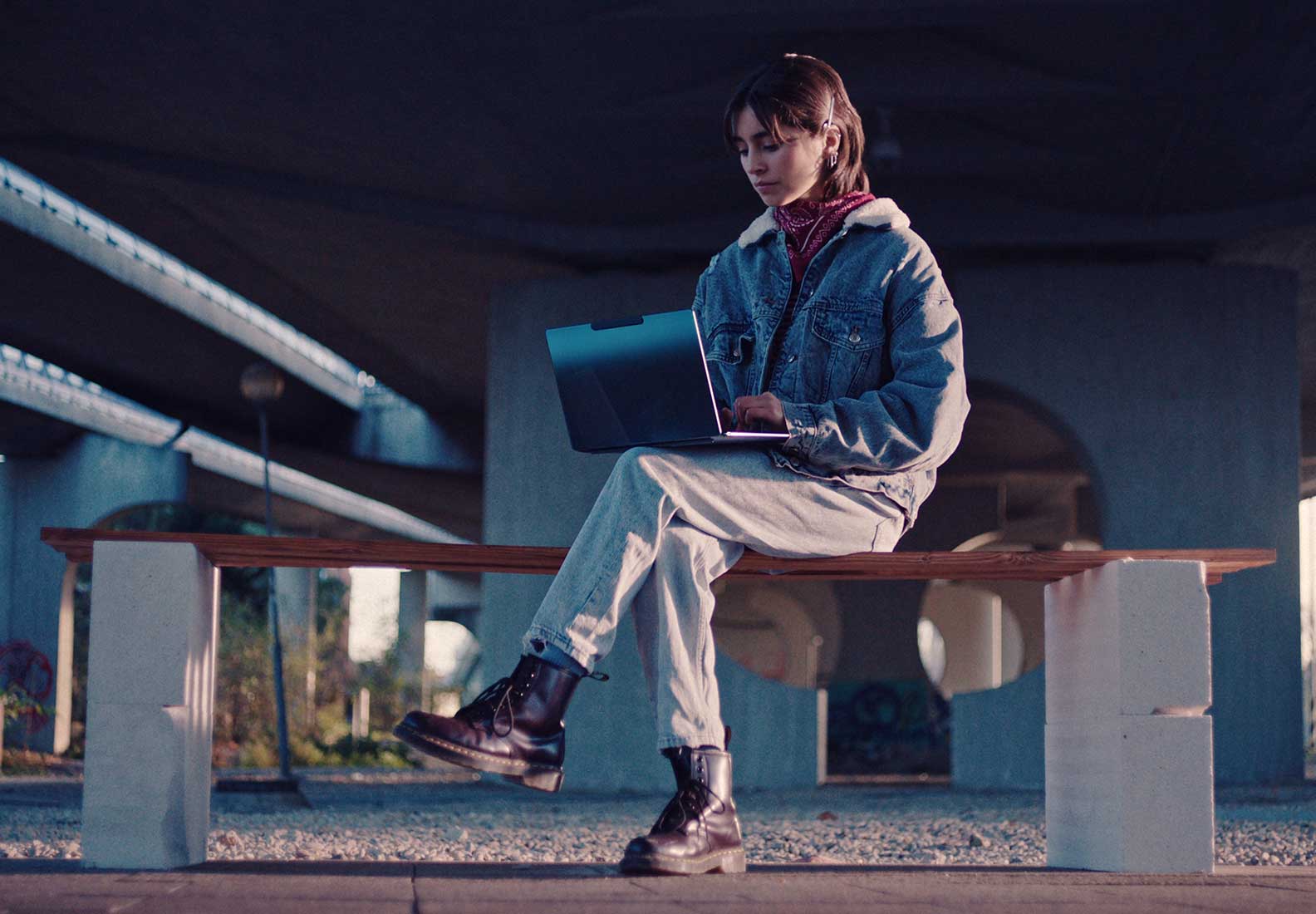 A woman sitting on an outdoor bench using her laptop