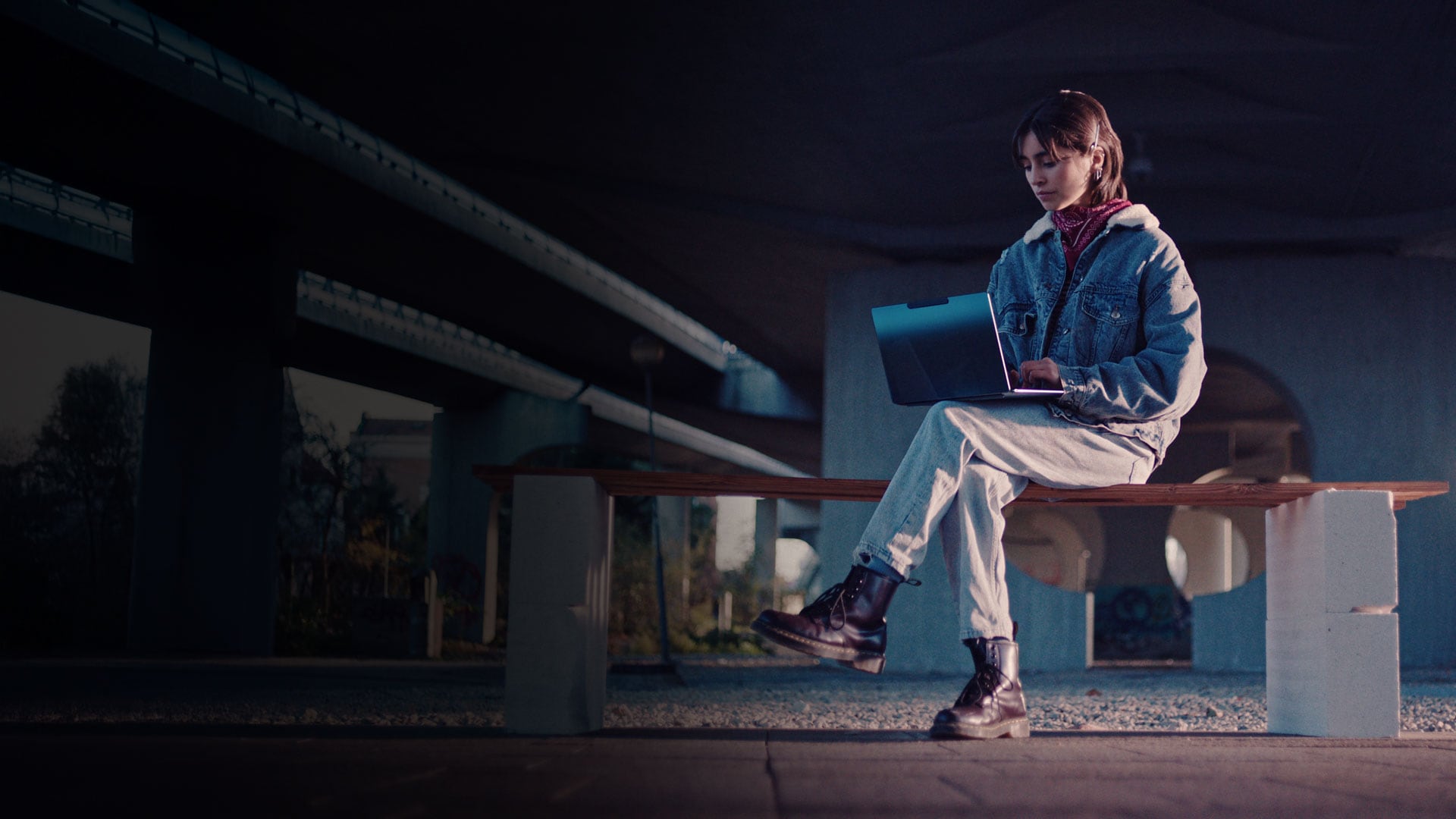 A woman sitting on an outdoor bench using her laptop