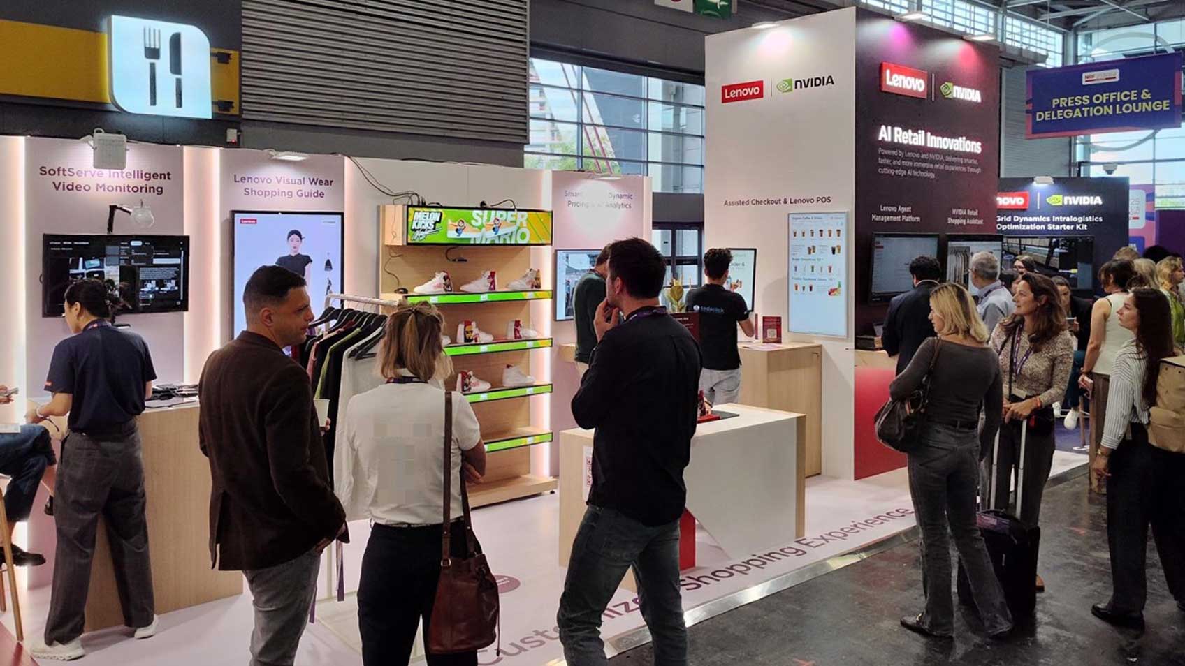 Asistentes a la conferencia de la National Retail Foundation en París interactuando con el stand de Lenovo diseñado como un entorno minorista real.