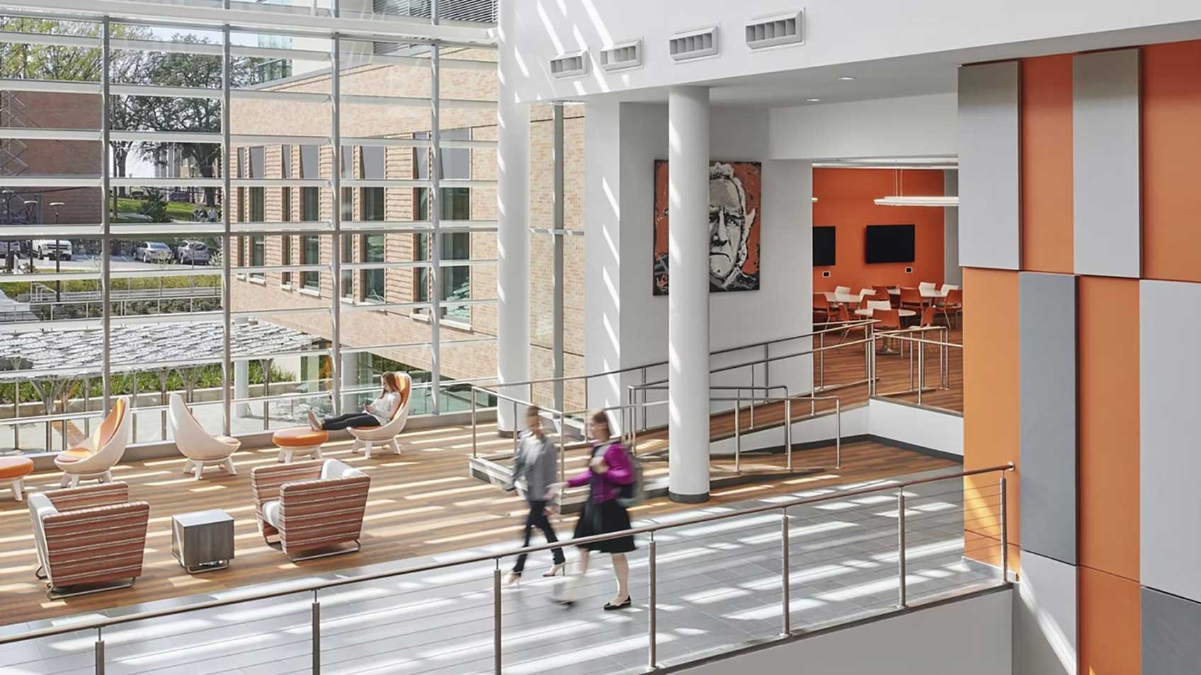 Dos personas caminando por un pasillo lleno de luz solar. 