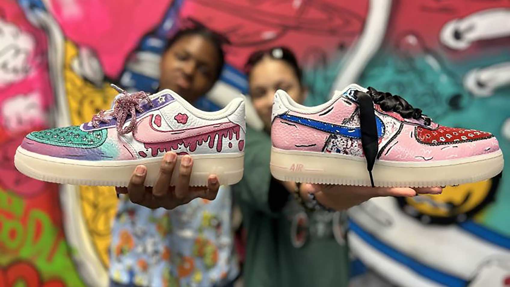 Dos personas sosteniendo los coloridos Sneaker Doodles que diseñaron personalmente. 