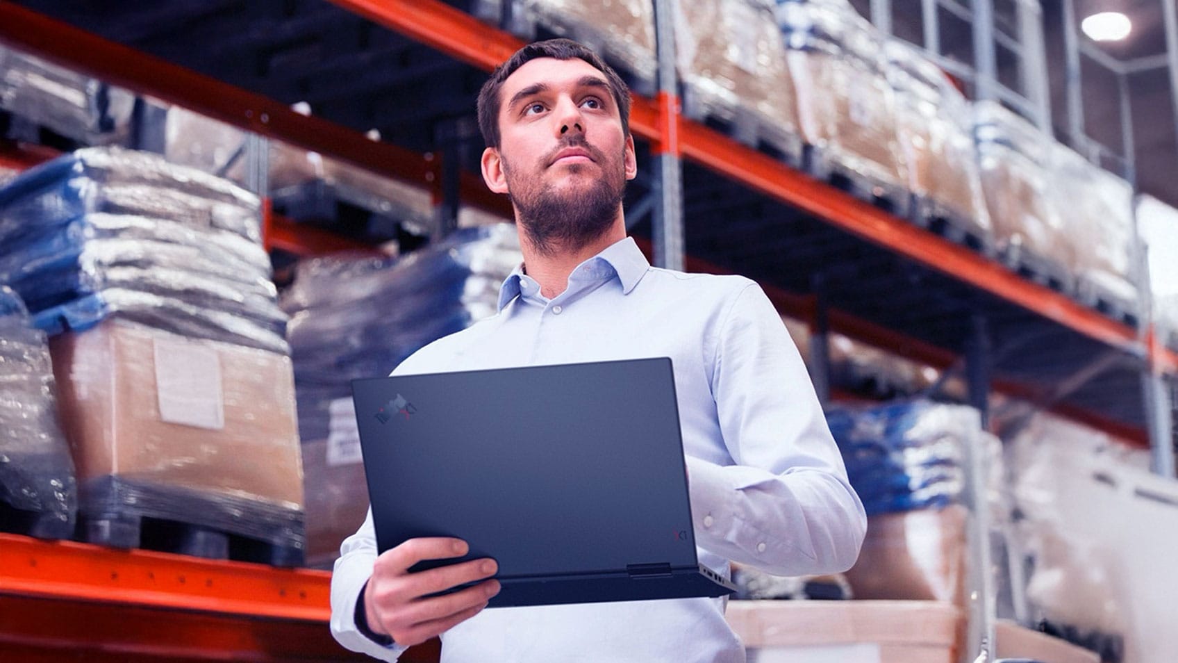 A man holding a laptop in a warehouse. 