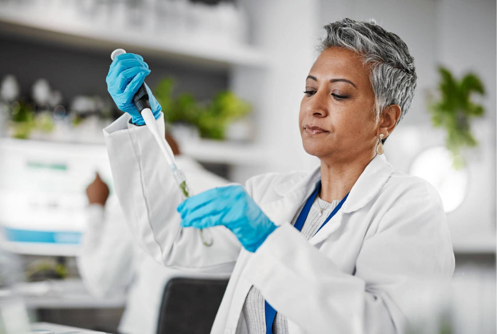 A woman in a white coat and gloves working in a lab