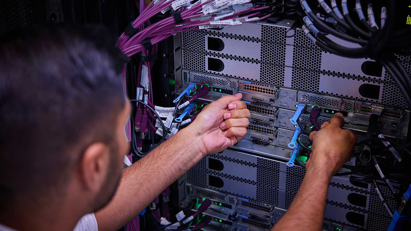 A man plugging cords into a server