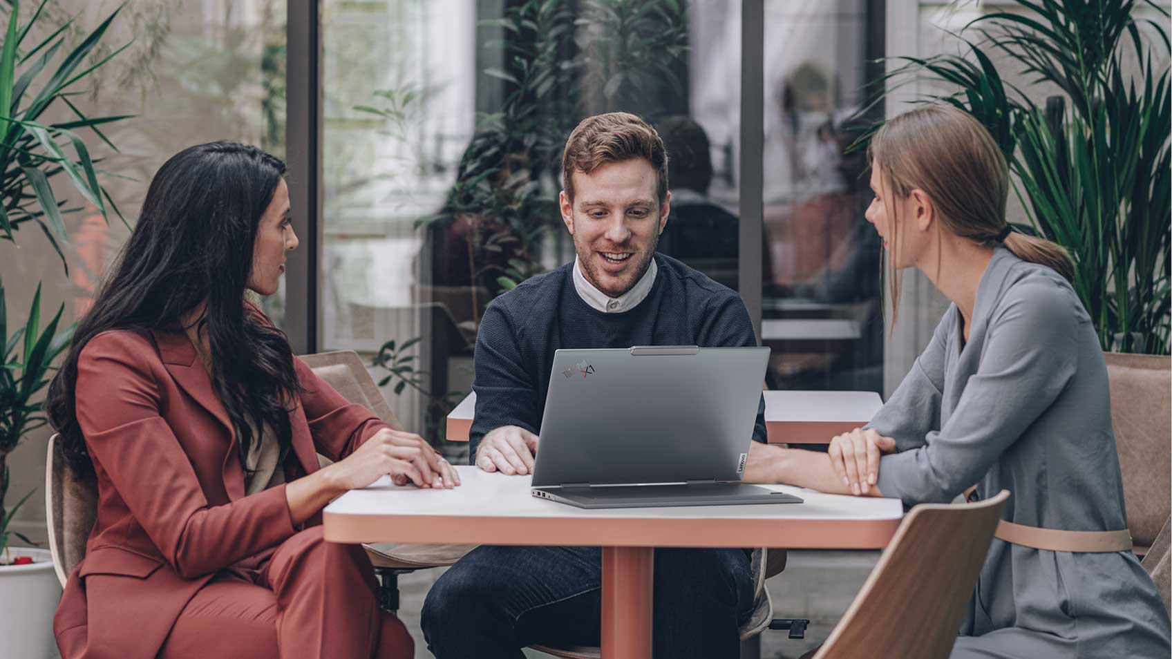 A man with a laptop sitting at a table with two women