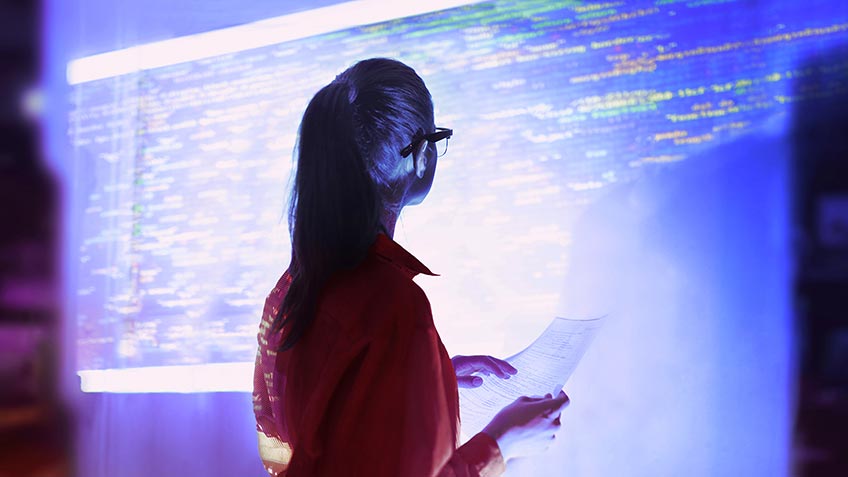 A woman looking at a large projection of data on the wall 