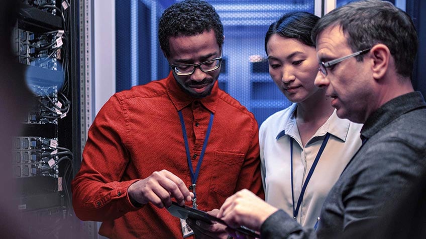 Three colleagues collaborating in a server room